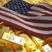Several gold bars are stacked together, with an American flag draped over them. The gold bars are marked as "Fine Gold 999.9" and "1000g. | GoldZeus.com