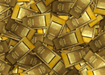 A large pile of shiny gold bars, each marked with weight and purity stamps, stacked in various directions and filling the entire frame. | GoldZeus.com