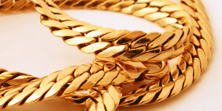 Close-up of intertwined gold chains with a shiny, reflective surface, showing the smooth, flat links and intricate details of the jewelry on a light background. | GoldZeus.com