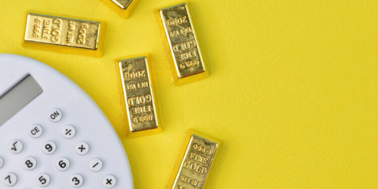 Five gold bars and a white calculator on a bright yellow background, suggesting financial calculations or investments related to gold. | GoldZeus.com