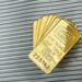 Several stacked gold bars, each labeled “CREDIT SUISSE ONE OUNCE FINE GOLD 999.9,” rest on a ribbed metallic surface. | GoldZeus.com